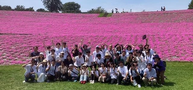 マザー牧場のピンクの花畑を背景に集まる日台の参加者